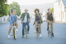 Portrait smiling friends sitting on bicycles on road — Stock Photo