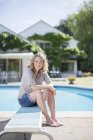 Frau sitzt auf Sprungbrett am Pool — Stockfoto