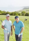 Старші чоловіки посміхаються на полі для гольфу з видом на океан — стокове фото