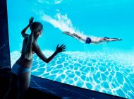 Mujer viendo novio bajo el agua en la piscina - foto de stock