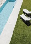 Cadeiras de salão na grama ao longo da piscina — Fotografia de Stock