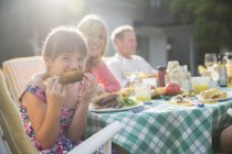 Mädchen isst Maiskolben am Tisch im Hinterhof — Stockfoto