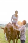Smiling couple horseback riding in rural pasture — Stock Photo