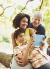 Multi-generation family using digital tablet outdoors — Stock Photo