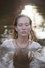 Спокойная женщина с закрытыми глазами в реке — стоковое фото