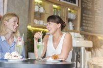 Women talking and drinking at cafe table — Stock Photo