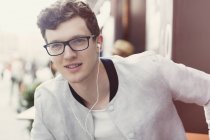 Портрет улыбающегося человека в очках, слушающего музыку в наушниках — стоковое фото