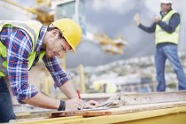 Bauarbeiter schreibt auf Klemmbrett auf Baustelle — Stockfoto