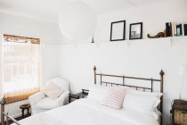 Shelf above bed in white bedroom — Stock Photo