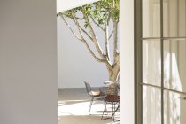 Mesa, cadeiras e árvore no pátio — Fotografia de Stock