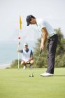 Kaukasischer Caddy beobachtet Mann beim Putten auf Golfplatz — Stockfoto