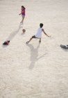 Children playing with soccer ball in sand — Stock Photo