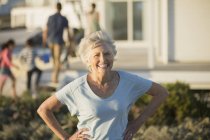Senior woman smiling with hands on hips outdoors — Stock Photo