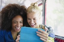 Захоплені друзі беруть селфі з цифровим планшетом на автобусі — стокове фото