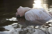 Женщина наклоняет голову назад в реку — стоковое фото