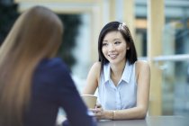 Des femmes d'affaires souriantes parlent pendant la pause café — Photo de stock