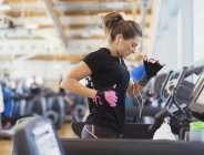 Woman running on treadmill at gym with headphones — Stock Photo