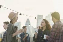 Young adult friends drinking and talking at rooftop party — Stock Photo