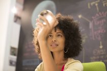 Mujer de negocios examinando bola de cristal en la oficina - foto de stock