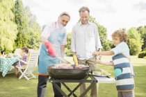 Men grilling meat on barbecue in backyard — Stock Photo