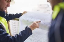 Engineers discussing blueprints at construction site — Stock Photo