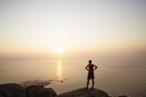Männliche Läufer auf Felsen mit Blick auf den Sonnenuntergang Meerblick — Stockfoto