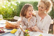 Mother and daughter eating in garden — Stock Photo
