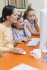 Madre e hijas usando computadora - foto de stock