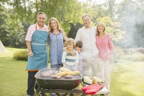 Famille multi-génération debout au barbecue dans la cour arrière — Photo de stock