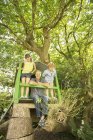 Feliz padre e hijos jugando en la casa del árbol - foto de stock