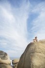 Casal sentado na formação de rocha na praia — Fotografia de Stock