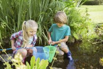 Enfants heureux pêchant ensemble dans l'étang — Photo de stock