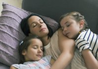 Serena madre e hijas durmiendo en el sofá - foto de stock