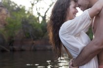 Casal abraço na beira do rio durante o dia — Fotografia de Stock