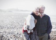 Couple aîné souriant marchant sur la plage — Photo de stock
