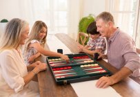 Abuelos y nietos jugando backgammon - foto de stock