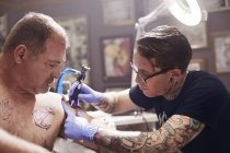 Tatoueur artiste tatouage homme épaule au studio — Photo de stock