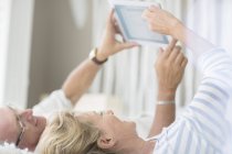 Пожилая пара с помощью цифрового планшета на кровати — стоковое фото