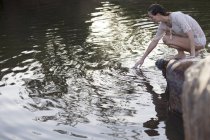 Donna immersione mano nel lago — Foto stock