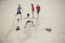 Дети играют в футбол с мячом в песке — стоковое фото