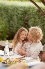 Mother and daughter sitting at table outdoors — Stock Photo