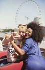 Amigos entusiastas tomando selfie en autobús de dos pisos con London Eye en segundo plano - foto de stock