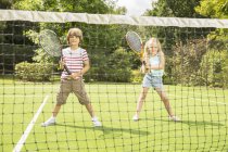 Niños jugando tenis en la cancha de hierba - foto de stock