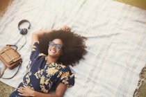 Vista aérea mujer sonriente con afro tendido en manta al aire libre - foto de stock