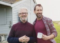 Portrait smiling father and son drinking coffee outside — Stock Photo
