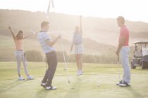 Jovens amigos entusiasmados no campo de golfe — Fotografia de Stock
