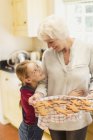 Granddaughter hugging grandmother baking gingerbread cookies — Stock Photo