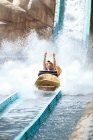 Begeisterter junger Mann reitet Wasserlog Vergnügungspark Fahrt — Stockfoto