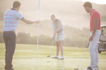 Caucasiano jovens amigos jogando golfe no campo — Fotografia de Stock