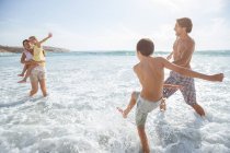 Familie spielt gemeinsam in Wellen am Strand — Stockfoto